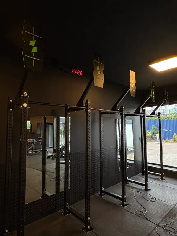 Krachtzone met een rij squat-racks en halters in een ruime sportschool